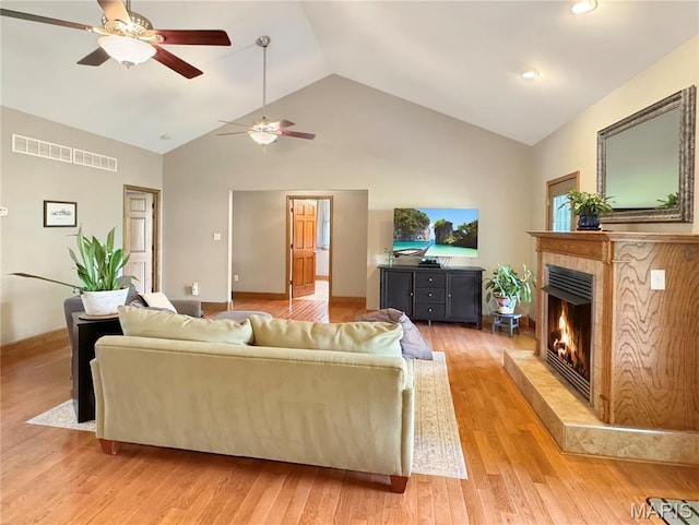 495 Oak Field Ct, Washington, MO 63090 - living area featuring a ceiling fan, a tiled fireplace, light wood-style flooring, high vaulted ceiling, and baseboards