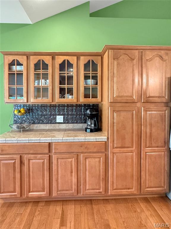 495 Oak Field Ct, Washington, MO 63090 - bar with vaulted ceiling, light wood finished floors, and backsplash