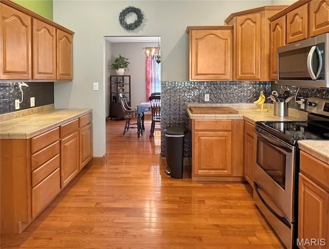 495 Oak Field Ct, Washington, MO 63090 - kitchen featuring appliances with stainless steel finishes, light wood-style floors, backsplash, and tile counters