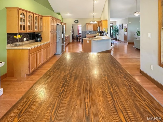 495 Oak Field Ct, Washington, MO 63090 - kitchen with stainless steel fridge with ice dispenser, lofted ceiling, decorative backsplash, glass insert cabinets, and light wood finished floors