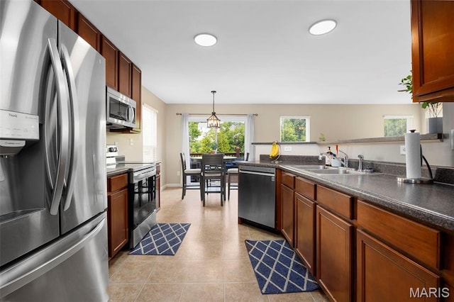 27 Brushy Brook Ct, Ofallon, MO 63366 - kitchen featuring appliances with stainless steel finishes, a sink, dark countertops, hanging light fixtures, and light tile patterned floors