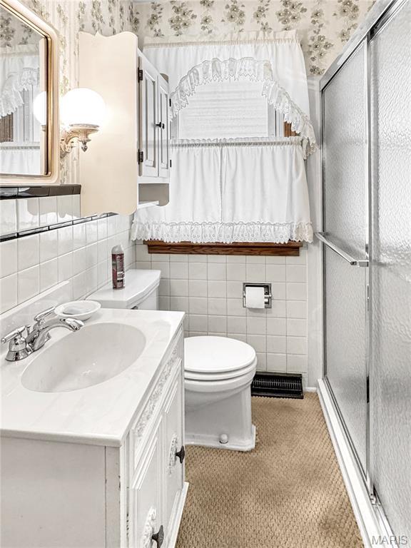 1508 3rd Pkwy, Washington, MO 63090 - bathroom featuring toilet, vanity, a shower stall, tile walls, and wallpapered walls