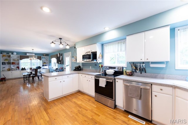 15701 County Road 1130, St James, MO 65559 - kitchen featuring stainless steel appliances, a peninsula, light countertops, white cabinetry, and light wood-style flooring