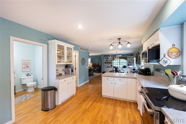15701 County Road 1130, St James, MO 65559 - kitchen with a peninsula, electric stove, stainless steel microwave, white cabinetry, and light wood-style floors