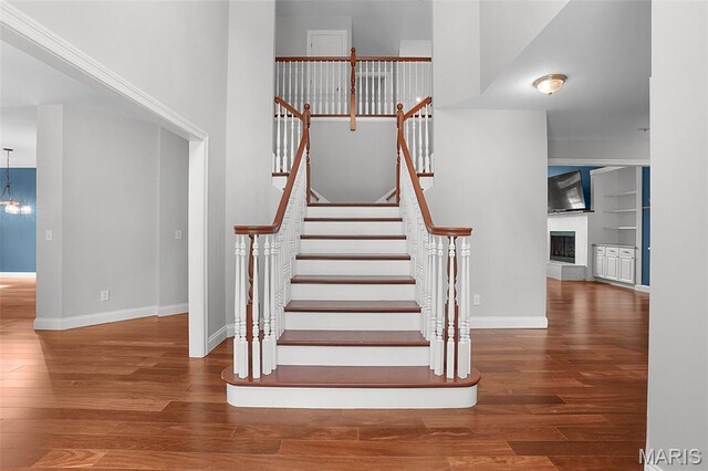 17917 Rosemar Ln, Wildwood, MO 63038 - staircase featuring wood finished floors, a fireplace with raised hearth, built in shelves, and a chandelier