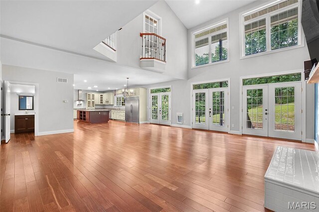 17917 Rosemar Ln, Wildwood, MO 63038 - unfurnished living room featuring french doors, a towering ceiling, hardwood / wood-style flooring, and a chandelier