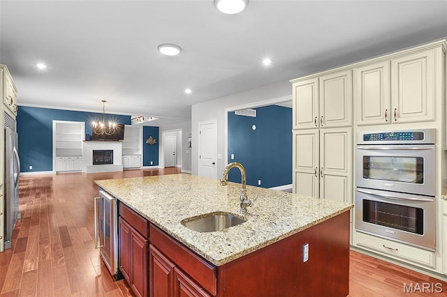 17917 Rosemar Ln, Wildwood, MO 63038 - kitchen featuring appliances with stainless steel finishes, cream cabinetry, a center island with sink, open floor plan, and a chandelier