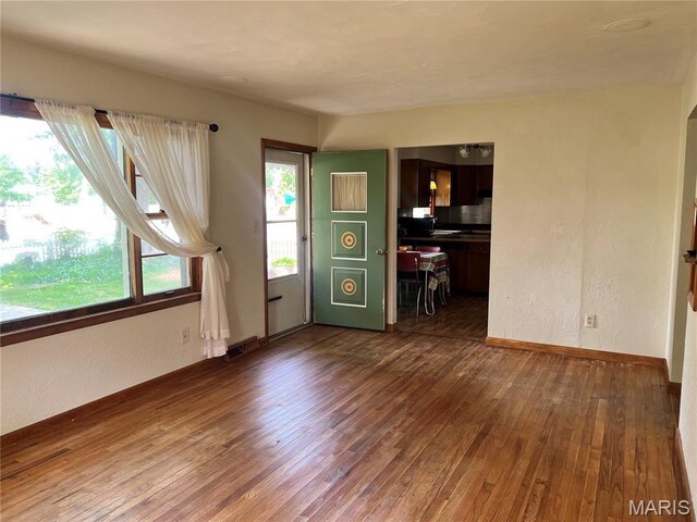 503 Cumberland St, Coffeen, IL 62017 - unfurnished living room featuring dark wood-style flooring, a textured wall, and baseboards