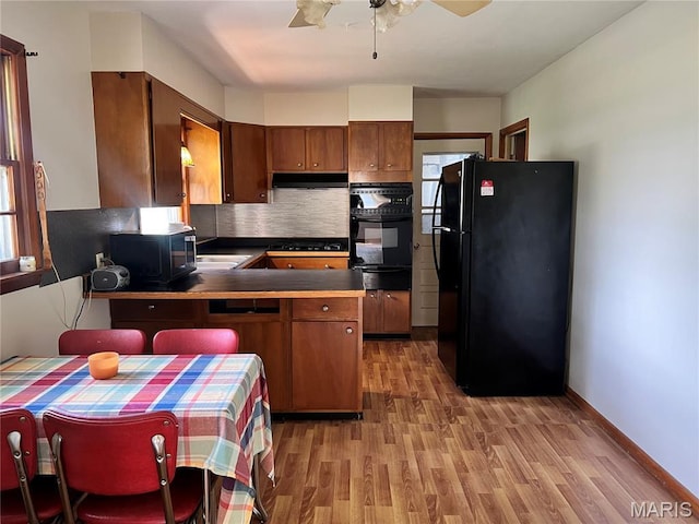503 Cumberland St, Coffeen, IL 62017 - kitchen with black appliances, light wood-style flooring, a warming drawer, a peninsula, and a ceiling fan