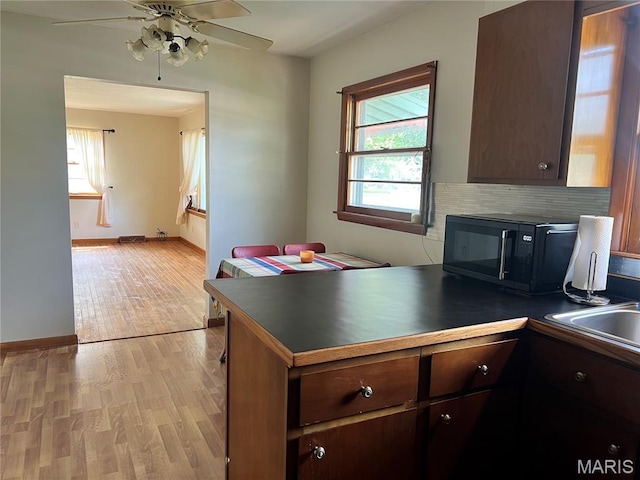 503 Cumberland St, Coffeen, IL 62017 - kitchen with black microwave, dark countertops, a peninsula, light wood-type flooring, and ceiling fan