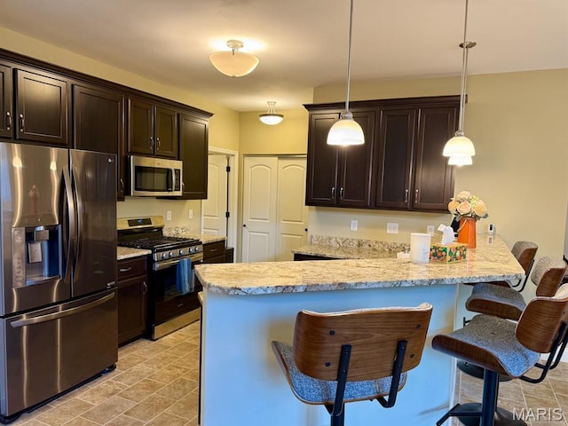 5005 Double Tree Dr, Imperial, MO 63052 - kitchen with stainless steel appliances, a kitchen bar, dark brown cabinetry, and hanging light fixtures