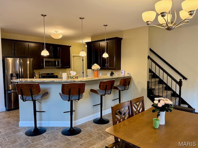 5005 Double Tree Dr, Imperial, MO 63052 - kitchen featuring appliances with stainless steel finishes, dark brown cabinetry, a peninsula, and light stone counters