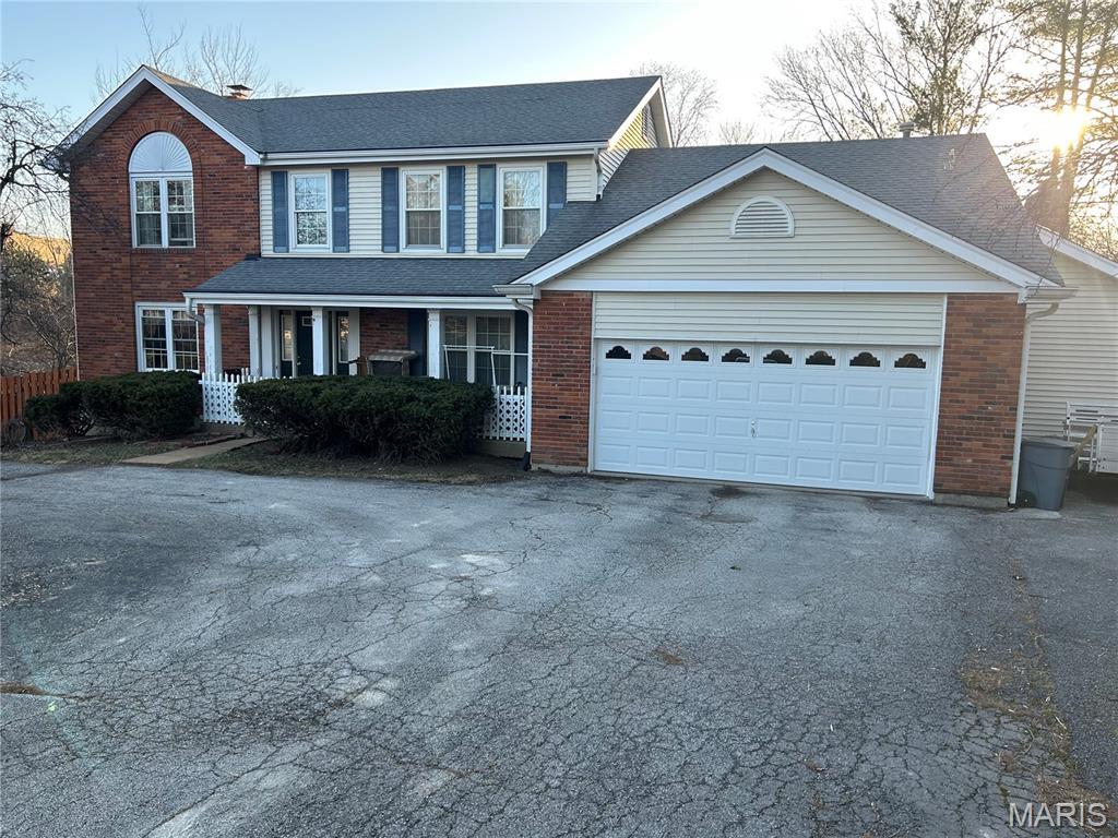 918 N Ballas Rd, Saint Louis, MO 63131 - view of front of property featuring brick siding, driveway, a porch, an attached garage, and a shingled roof