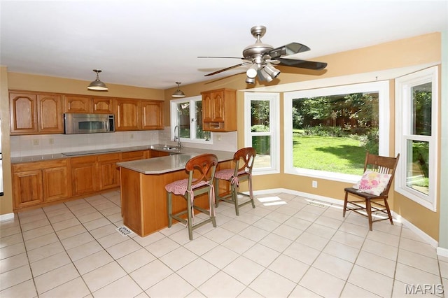 2003 Centennial Ct, Wildwood, MO 63011 - kitchen with stainless steel microwave, backsplash, black electric cooktop, a peninsula, and a breakfast bar