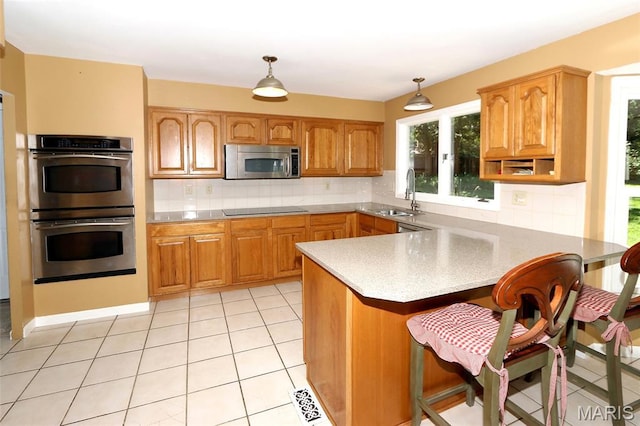2003 Centennial Ct, Wildwood, MO 63011 - kitchen featuring stainless steel appliances, a peninsula, decorative backsplash, a kitchen breakfast bar, and hanging light fixtures