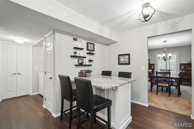 564 Sarah Ln Unit 103, Creve Coeur, MO 63141 - kitchen with a textured ceiling, a breakfast bar area, dark wood-style flooring, baseboards, and a chandelier