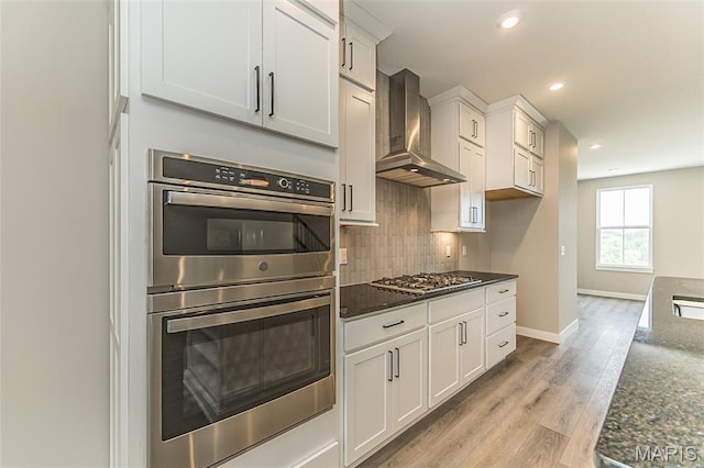 8923 Gateway Hts Unit 94-805, Richmond Heights, MO 63144 - kitchen featuring wall chimney range hood, stainless steel appliances, decorative backsplash, recessed lighting, and dark stone counters