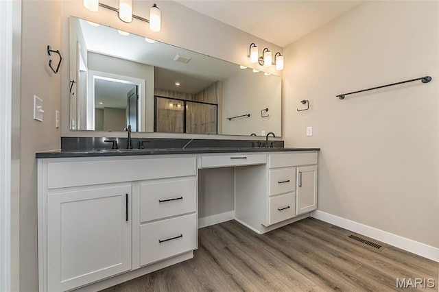 8923 Gateway Hts Unit 94-805, Richmond Heights, MO 63144 - bathroom featuring double vanity, baseboards, wood finished floors, and a shower with shower door