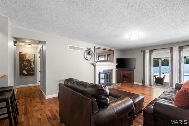 116 Lea Meadows Dr, Ballwin, MO 63011 - living area with wood finished floors, a textured ceiling, baseboards, and a glass covered fireplace