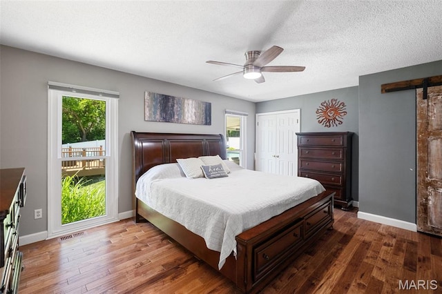 116 Lea Meadows Dr, Ballwin, MO 63011 - bedroom with a barn door, multiple windows, wood finished floors, baseboards, and a textured ceiling