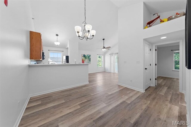 9740 Bexley Station Dr Unit 7J, Concord Township, MO 63123 - kitchen with brown cabinetry, freestanding refrigerator, a chandelier, high vaulted ceiling, and light wood finished floors