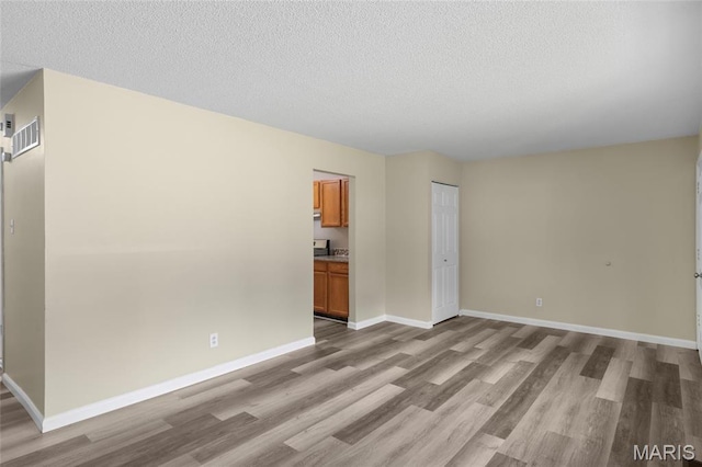 220 Versailles Dr, Florissant, MO 63031 - unfurnished living room with light wood-type flooring and a textured ceiling