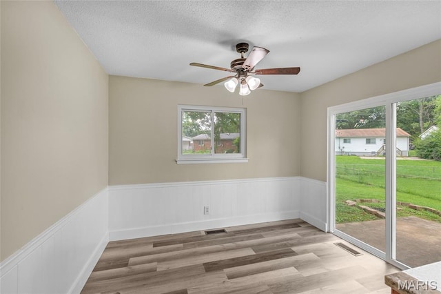 220 Versailles Dr, Florissant, MO 63031 - empty room featuring ceiling fan, a wainscoted wall, a textured ceiling, and wood finished floors