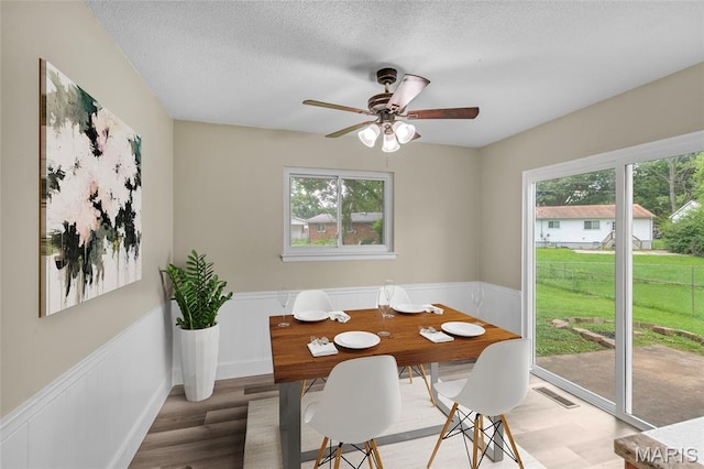 220 Versailles Dr, Florissant, MO 63031 - dining area with healthy amount of natural light, light wood-style floors, a wainscoted wall, ceiling fan, and a textured ceiling