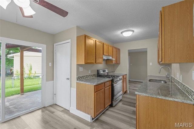 220 Versailles Dr, Florissant, MO 63031 - kitchen featuring stainless steel gas range oven, under cabinet range hood, light wood-type flooring, stone countertops, and a ceiling fan