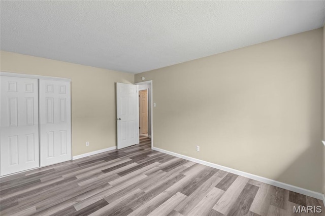220 Versailles Dr, Florissant, MO 63031 - unfurnished bedroom featuring wood finished floors, a closet, and a textured ceiling