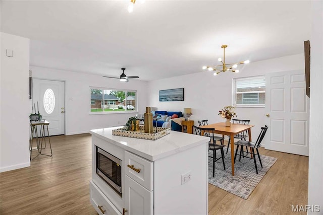 216 Clearpoint Ln, Saint Louis, MO 63123 - kitchen with stainless steel microwave, healthy amount of natural light, a center island, and light wood finished floors