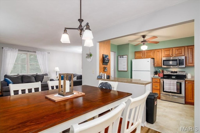 1170 Bond St, Carlyle, IL 62231 - kitchen featuring stainless steel appliances, brown cabinetry, open floor plan, ceiling fan, and pendant lighting