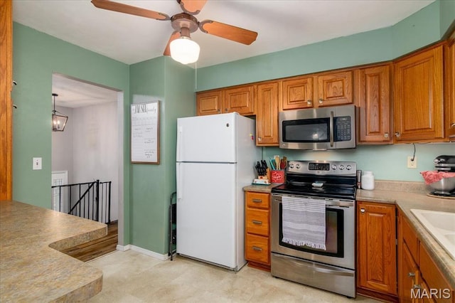 1170 Bond St, Carlyle, IL 62231 - kitchen with stainless steel appliances, brown cabinetry, light countertops, ceiling fan, and light floors