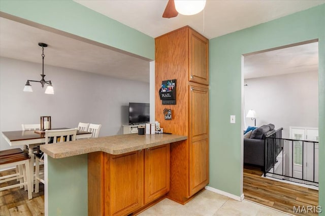 1170 Bond St, Carlyle, IL 62231 - kitchen with ceiling fan, a peninsula, light wood-type flooring, hanging light fixtures, and light countertops