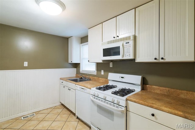 8217 Buchanan Ave, Saint Louis, MO 63114 - kitchen with white appliances, white cabinets, wainscoting, and light tile patterned flooring