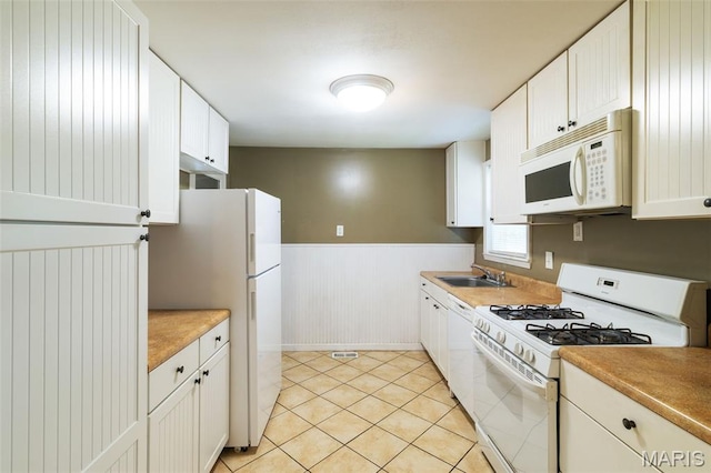 8217 Buchanan Ave, Saint Louis, MO 63114 - kitchen with white appliances, a wainscoted wall, white cabinetry, light tile patterned flooring, and light countertops