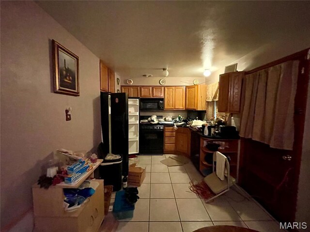 329 Kirk Dr, Ferguson, MO 63135 - kitchen with black appliances, light tile patterned floors, dark countertops, and brown cabinetry
