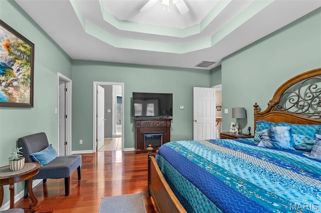 807 Caribou Ct, Cape Girardeau, MO 63701 - bedroom with wood finished floors, a raised ceiling, a glass covered fireplace, and a ceiling fan