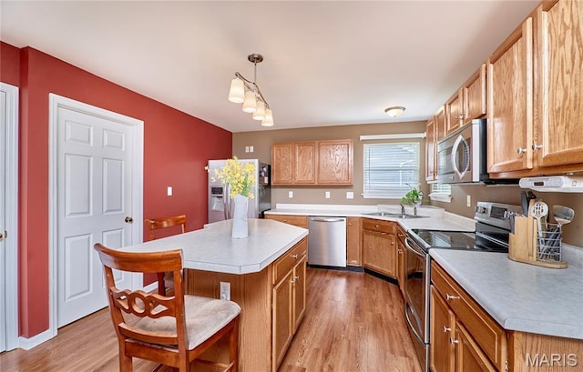 2052 Peine Frst, Wentzville, MO 63385 - kitchen with appliances with stainless steel finishes, light wood finished floors, light countertops, a kitchen island, and a kitchen breakfast bar