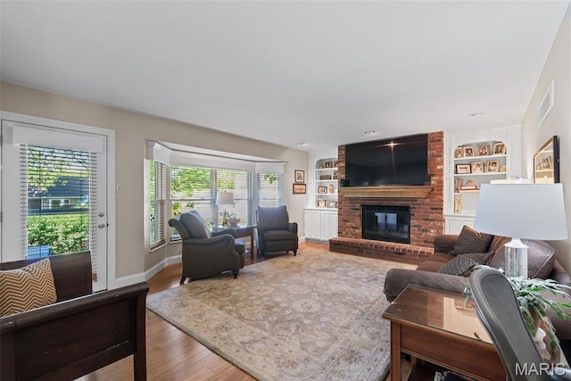 113 Christine Cay Ct, Saint Charles, MO 63304 - living area with wood finished floors, a brick fireplace, built in features, and baseboards