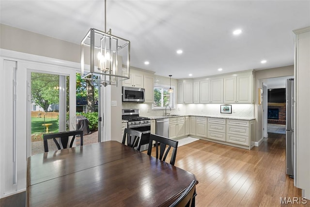 113 Christine Cay Ct, Saint Charles, MO 63304 - dining space with a chandelier, light wood-type flooring, recessed lighting, and a brick fireplace