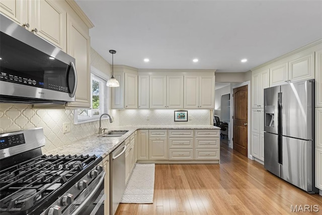 113 Christine Cay Ct, Saint Charles, MO 63304 - kitchen featuring stainless steel appliances, a sink, light wood-type flooring, light stone counters, and backsplash