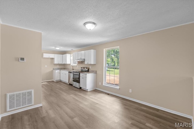 206 6th St, Park Hills, MO 63601 - kitchen with stainless steel appliances, wood finished floors, white cabinets, a textured ceiling, and baseboards