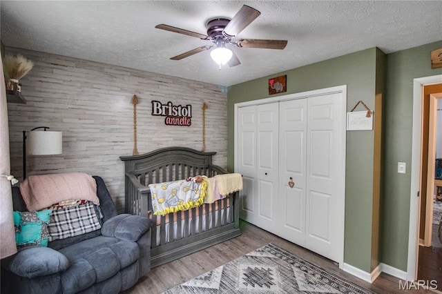906 E Fairgrounds Ave, Jerseyville, IL 62052 - bedroom with a closet, a textured ceiling, wood finished floors, ceiling fan, and a nursery area