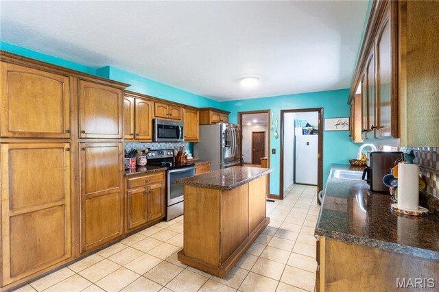 465 County Road 5120, Salem, MO 65560 - kitchen featuring stainless steel appliances, a kitchen island, brown cabinets, light tile patterned flooring, and tasteful backsplash