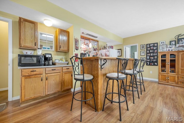1020 Oak Creek Ln, Waterloo, IL 62298 - indoor dry bar featuring black microwave, light wood-type flooring, freestanding refrigerator, and baseboards