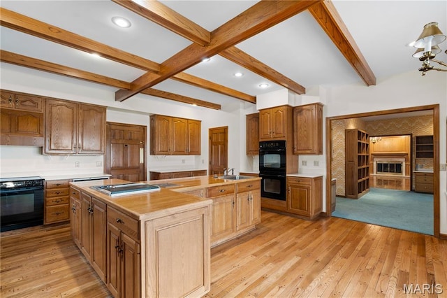305 Ridge Dr, Sikeston, MO 63801 - kitchen with a kitchen island with sink, beamed ceiling, light wood finished floors, light countertops, and a sink