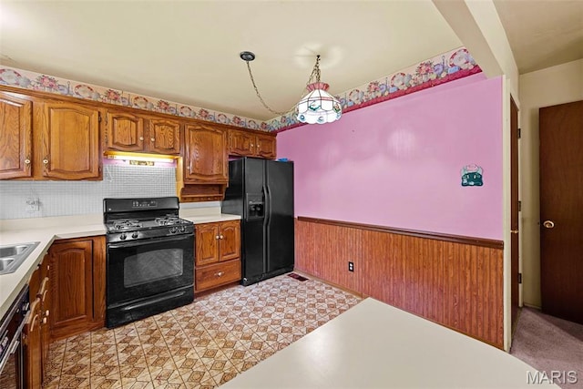 1466 Friar Tuck Ln, Lemay Township, MO 63125 - kitchen featuring black appliances, a wainscoted wall, light countertops, brown cabinetry, and under cabinet range hood