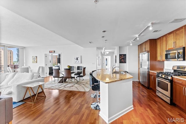4909 Laclede Ave Unit 806, Saint Louis, MO 63108 - kitchen featuring appliances with stainless steel finishes, open floor plan, wood finished floors, and a kitchen bar