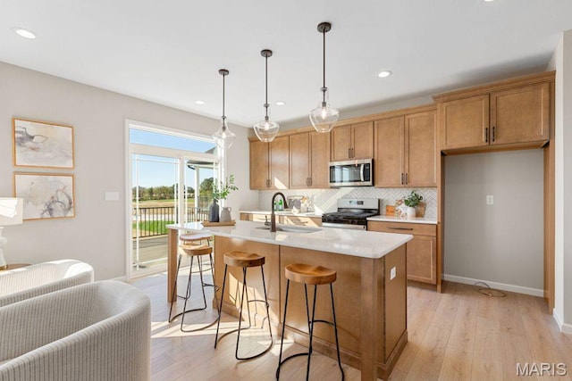 543 Wheatfield Cir, Ofallon, MO 63385 - kitchen with stainless steel appliances, a sink, light wood-style flooring, tasteful backsplash, and light countertops